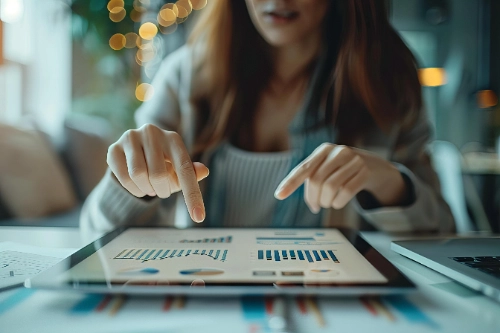 Una mujer utilizando los dedos para analizar gráficos de barras y pasteles de rendimiento financiero en una tableta digital