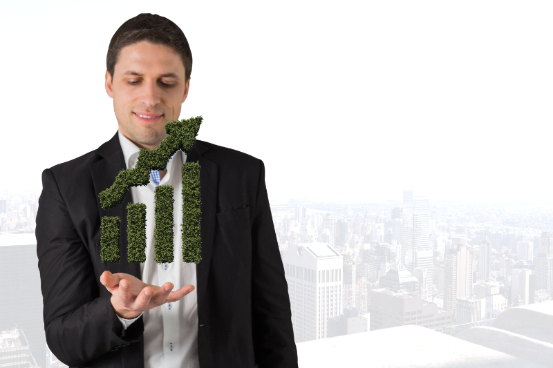 Ejecutivo sosteniendo un gráfico de barras hecho de césped, representando el crecimiento sostenible y las finanzas ecológicas.